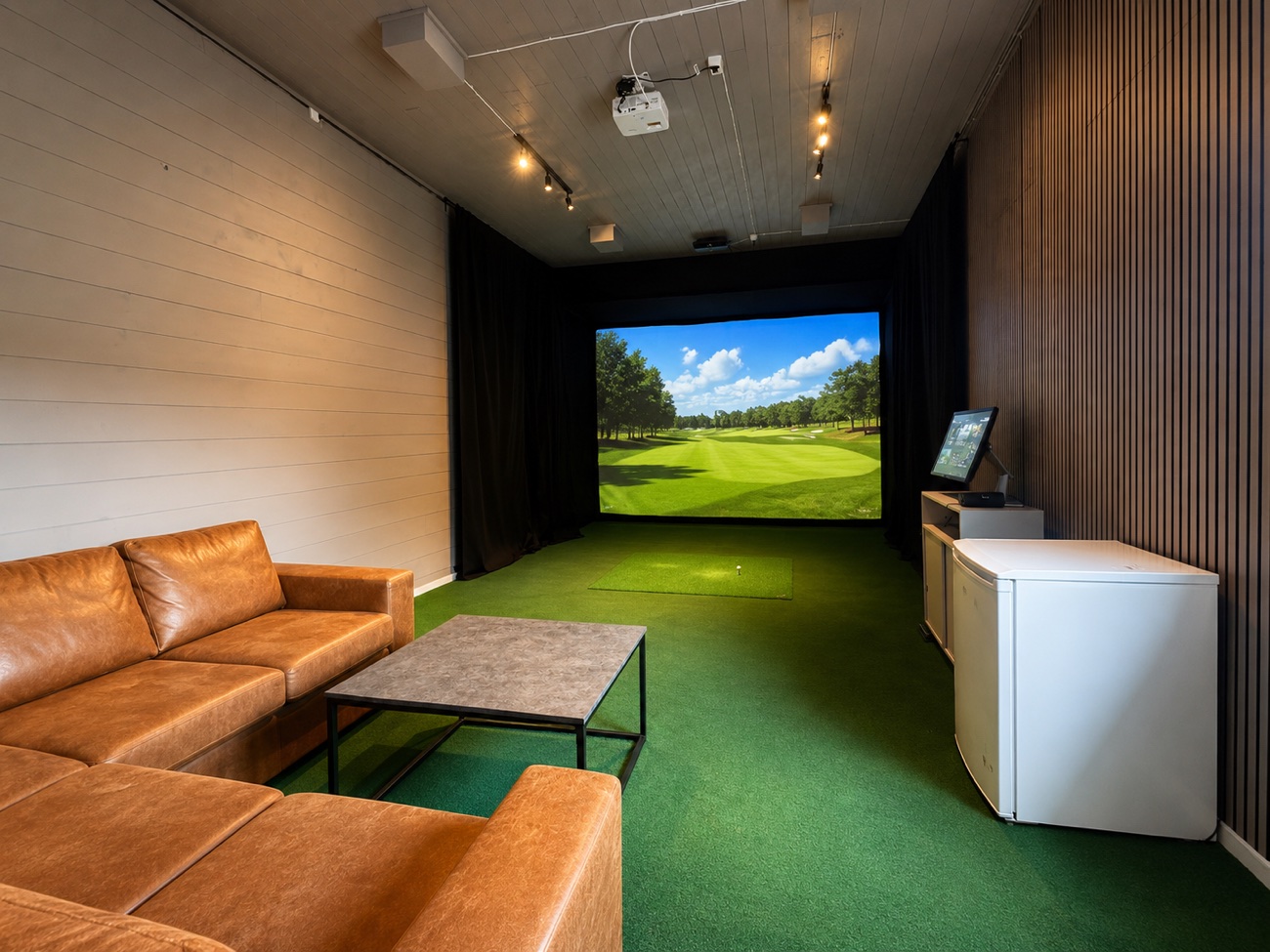 Privat loungeområde med skinnsofa og Trackman iO-skjerm